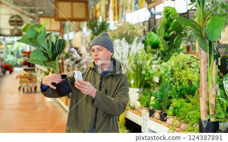 Man photographing artificial plant in home goods store 124387891