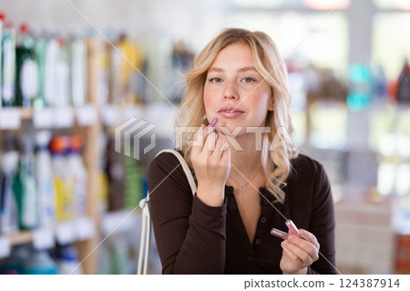 Girl housewife in cosmetic store examines goods, chooses facial powder 124387914