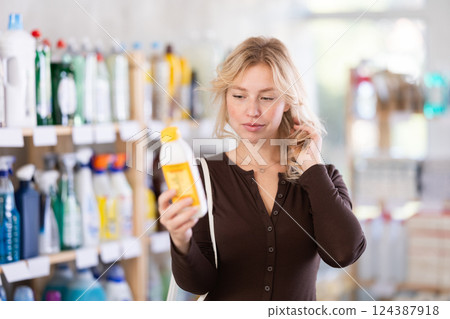 Happy young woman choosing hair care treatments in cosmetics store 124387918