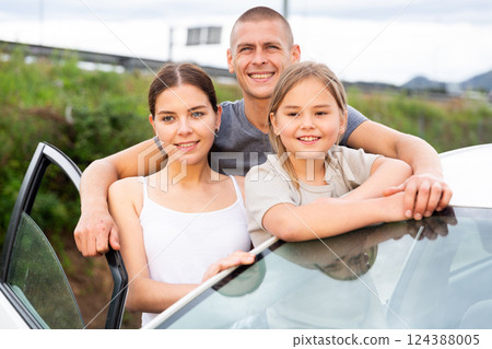 Positive family standing near an open car 124388005