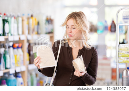 Girl housewife in household store examines goods, chooses washcloth Girl housewife in household store examines goods, chooses washcloth 124388057