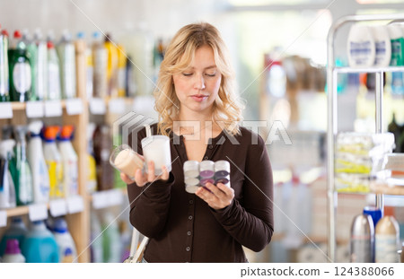 Positive young woman picking candles for home in shop 124388066