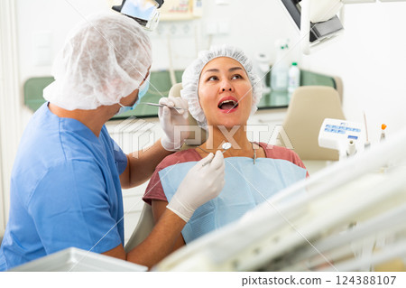 Dentist examines the oral cavity of female patient. Dental treatment in dental clinic 124388107