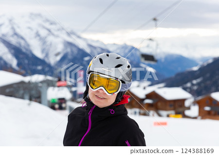 Positive woman in ski helmet and glasses enjoying vacation in ski resort Positive woman in ski helmet and glasses enjoying vacation in ski resort 124388169