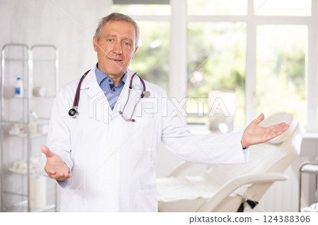 Elderly male doctor posing in medical office Elderly male doctor posing in medical office 124388306
