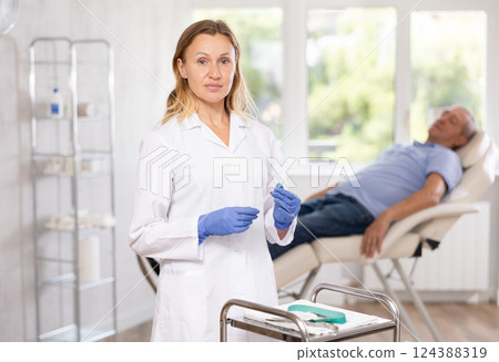 Focused female doctor preparing syringes for injection in clinic office Focused female doctor preparing syringes for injection in clinic office 124388319