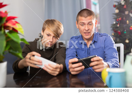 Boy with father playing on phones during Christmas 124388408