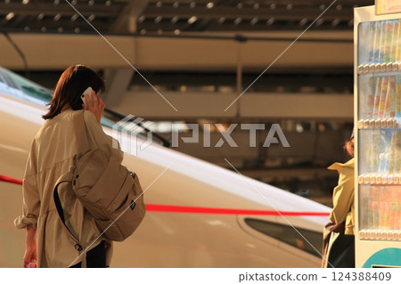 A woman making a phone call from the Shinkansen platform 124388409
