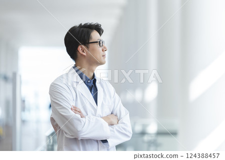A man in his 40s wearing a white coat and folding his arms, profile 124388457