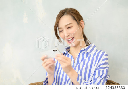 Smiling woman looking at smartphone 124388880
