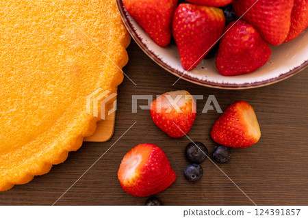 Sponge cake on the table. The process of making strawberry pie. Strawberries  124391857