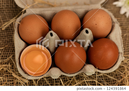 Brown homemade eggs in an egg carton. Broken egg. Raw egg yolk 124391864