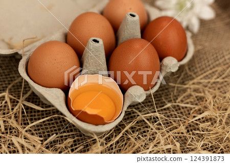 Brown homemade eggs in an egg carton. Broken egg. Raw egg yolk 124391873