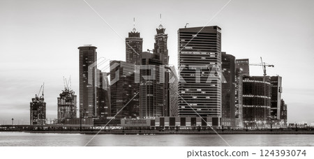 Urban city skyline with illuminated skyscrapers and waterfront railing in black and white at night, Dubai Marina bay UAE 124393074