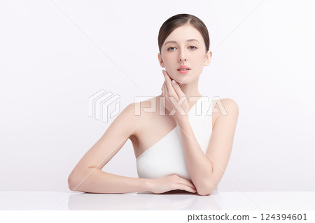 A beautiful young woman with clean, fresh skin against a white background. Skincare, facial treatment, cosmetology, beauty, and spa. An elegant portrait of an woman. 124394601