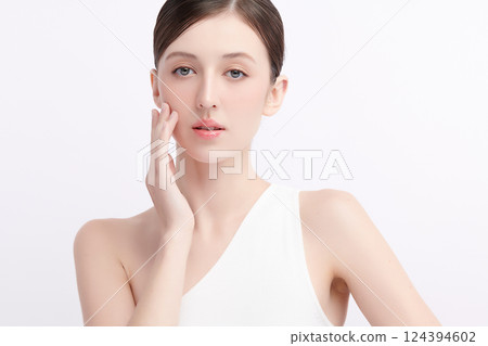 A beautiful young woman with clean, fresh skin against a white background. Skincare, facial treatment, cosmetology, beauty, and spa. An elegant portrait of an woman. 124394602