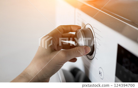 woman's hand sets the washing program 124394700