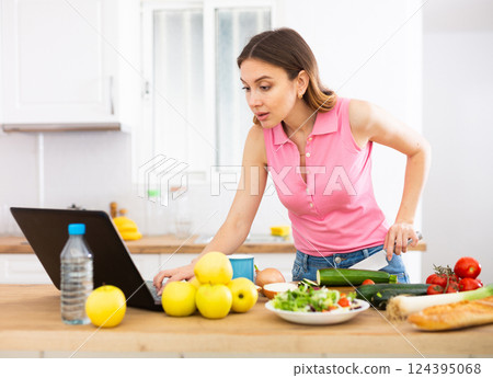 Woman cooking salad recipe from the Internet Woman cooking salad recipe from the Internet 124395068