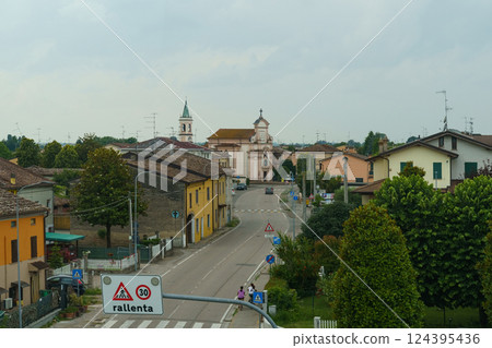 Charming Italian village street view with colorful houses and a distant church during an overcast afternoon 124395436