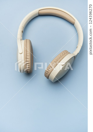 Modern wireless headphones lying on minimalist blue background Modern wireless headphones lying on minimalist blue background 124396270
