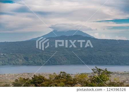 Volcano with a blue sky surrounded by green vegetation, Nicaragua. View of a beautiful volcano on a sunny day surrounded by vegetation 124396326