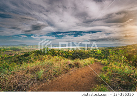 Landscape of a dirt road overlooking Masaya Lagoon. Nature trail overlooking a distant volcano 124396330