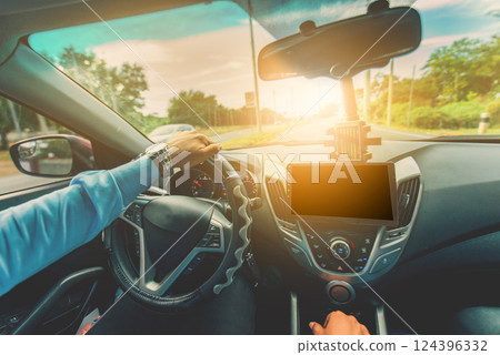 Driver hands on the steering wheel while driving on the asphalt. View of the driver hands driving on the highway 124396332