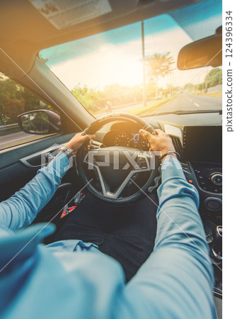 View of a driver holding the steering wheel and driving on the road View of a driver holding the steering wheel and driving on the road 124396334