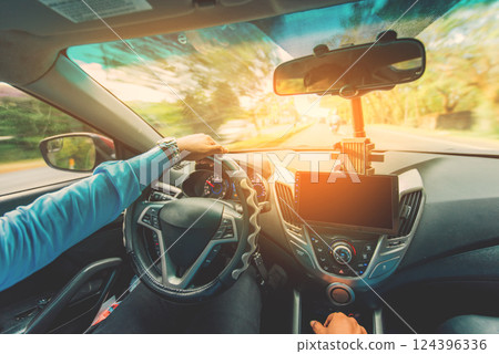 View of the driver hands driving on the highway. Driver hands on the steering wheel while driving on the asphalt View of the driver hands driving on the highway. Driver hands on the steering wheel while driving on the asphalt 124396336