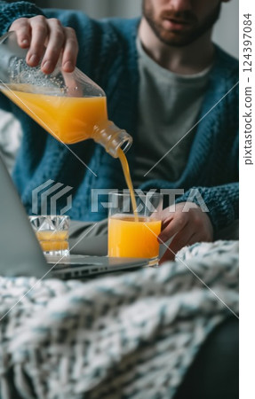 person pouring fresh orange juice from jug to drinking glass 124397084