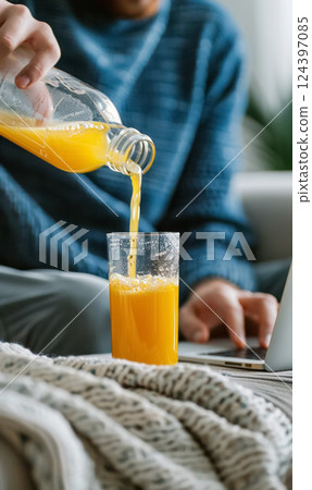 person pouring fresh orange juice from jug to drinking glass 124397085