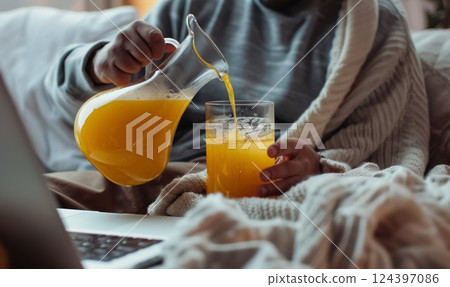 person pouring fresh orange juice from jug to drinking glass 124397086