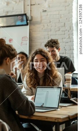 Diverse group of young professionals focused on brainstorming and collaboration in creative office space, working together on laptops, demonstrating teamwork and innovation 124397186