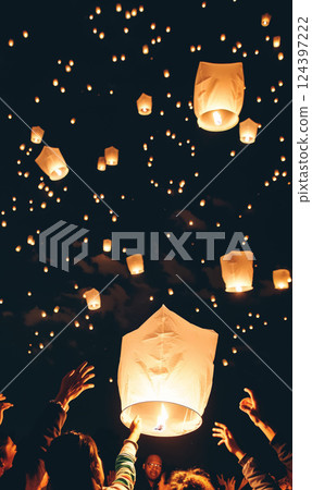 Glowing paper lanterns float into night sky during festive gathering, symbolizing hope and unity, as people release them in warm, communal celebration Glowing paper lanterns float into night sky during festive gathering, symbolizing hope and unity, as people release them in warm, communal celebration 124397222