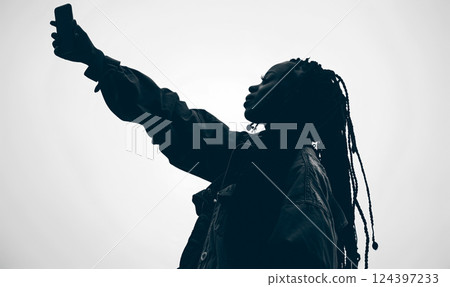 silhouette of black african american woman taking selfie in minimalist black and white setting, highlighting her braided hairstyle and modern, stylish look 124397233