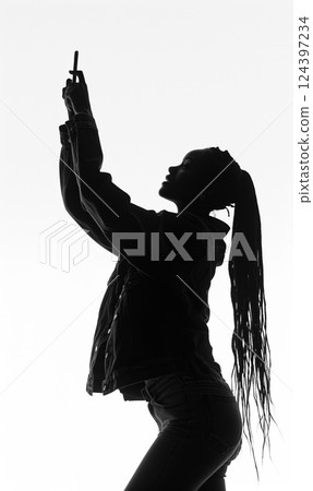 silhouette of black african american woman taking selfie in minimalist black and white setting, highlighting her braided hairstyle and modern, stylish look 124397234