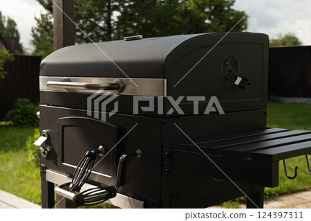 New portable charcoal barbecue grill for summer party at patio. Summer. Outdoors. BBQ grill. Close up. New portable charcoal barbecue grill for summer party at patio. Summer. Outdoors. BBQ grill. Close up. 124397311