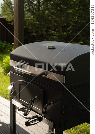 New portable charcoal barbecue grill for summer party at patio. Summer. Outdoors. BBQ grill. New portable charcoal barbecue grill for summer party at patio. Summer. Outdoors. BBQ grill. 124397315