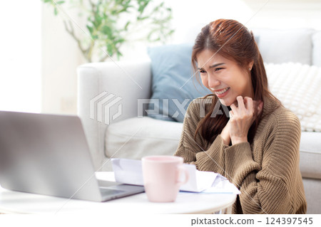 Young asian woman using laptop with happy and satisfaction in living room at home. 124397545