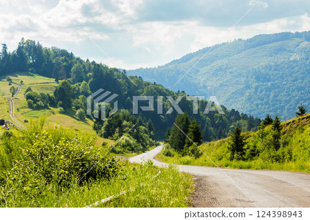 old country road winding through mountainous countryside. rural scenery. wonderful summer landscape. spruce forest along the way. bright sunny weather. travel backcountry concept old country road winding through mountainous countryside. rural scenery. wonderful summer landscape. spruce forest along the way. bright sunny weather. travel backcountry concept 124398943