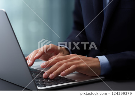 在筆記型電腦鍵盤上打字的手的特寫。穿著西裝的商人在辦公室的辦公桌上工作 在筆記型電腦鍵盤上打字的手的特寫。穿著西裝的商人在辦公室的辦公桌上工作 124399379