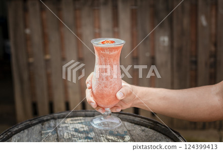 Hands holding strawberry smoothie on wooden table with blurred background. Hands showing strawberry smoothie on wooden table. People hand holding a strawberry milkshake on wood Hands holding strawberry smoothie on wooden table with blurred background. Hands showing strawberry smoothie on wooden table. People hand holding a strawberry milkshake on wood 124399413