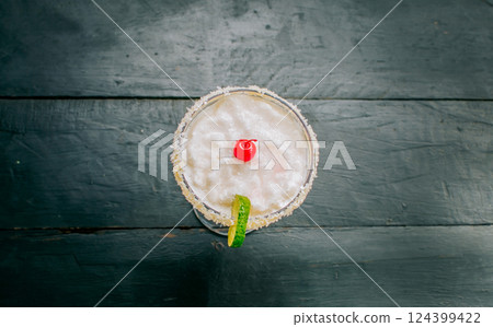 Top view of delicious frozen coconut cocktail with cherry. Coconut margarita with cherry on wooden table 124399422