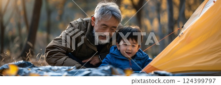 A heartwarming moment between a grandfather and grandson while camping in the serene outdoors, enjoying nature together. A heartwarming moment between a grandfather and grandson while camping in the serene outdoors, enjoying nature together. 124399797
