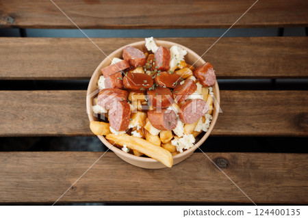 Poutine fries with chees and sausage in paper takeout container. Delicious freshly prepared meal, perfect for menus, restaurants, or food delivery concepts. Poutine fries with chees and sausage in paper takeout container. Delicious freshly prepared meal, perfect for menus, restaurants, or food delivery concepts. 124400135