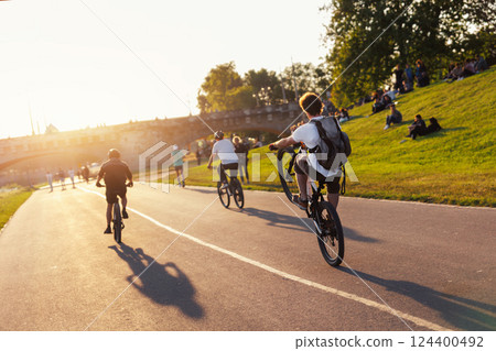 Scenic view youth people ride bicycles sunny Dresden Elbe riverside path against warm sunset glow active leisure. Rider perform wheelie beside historic Augustus bridge crowd relaxes grass lawn meadow Scenic view youth people ride bicycles sunny Dresden Elbe riverside path against warm sunset glow active leisure. Rider perform wheelie beside historic Augustus bridge crowd relaxes grass lawn meadow 124400492