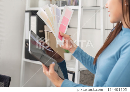 Color Choice and Design Collaboration. A designer weighing color options and utilizing a tablet for project inspiration. 124401505