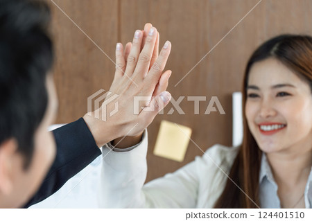 Collaboration and Teamwork. A celebratory high-five highlights a successful partnership in a professional setting. 124401510