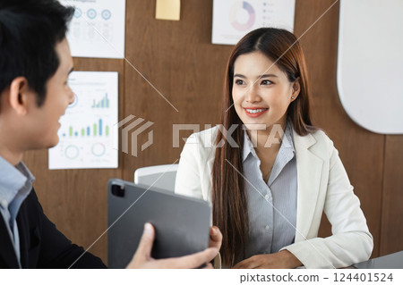 Business Collaboration and Professional Discussion. A man and woman engaging in conversation over business strategies in a modern office setting. 124401524