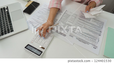 Tax Preparation and Financial Review. A woman carefully reviews her documents while planning her finances. 124401530